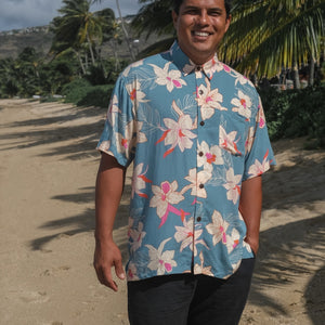 man wearing a teal aloha button up shirt with cream colored orchid pattern