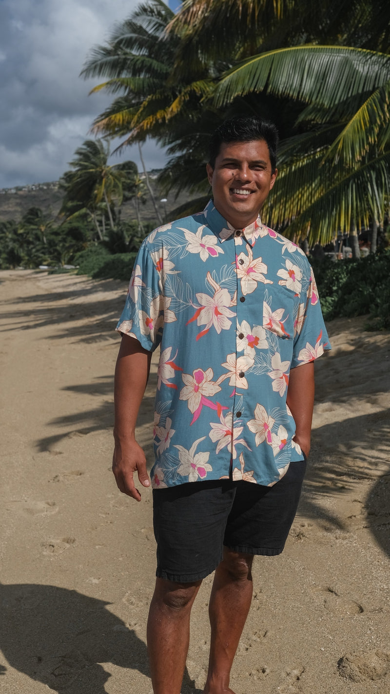 man wearing a teal aloha button up shirt with cream colored orchid pattern