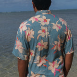 man wearing a teal aloha button up shirt with cream colored orchid pattern