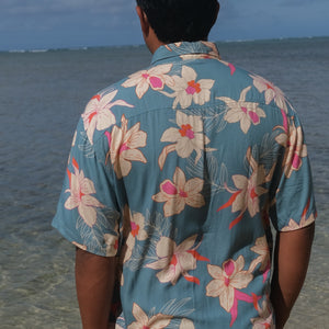man wearing a teal aloha button up shirt with cream colored orchid pattern