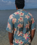 man wearing a teal aloha button up shirt with cream colored orchid pattern