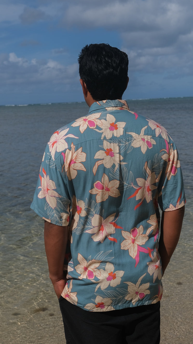 man wearing a teal aloha button up shirt with cream colored orchid pattern