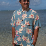 man wearing a teal aloha button up shirt with cream colored orchid pattern