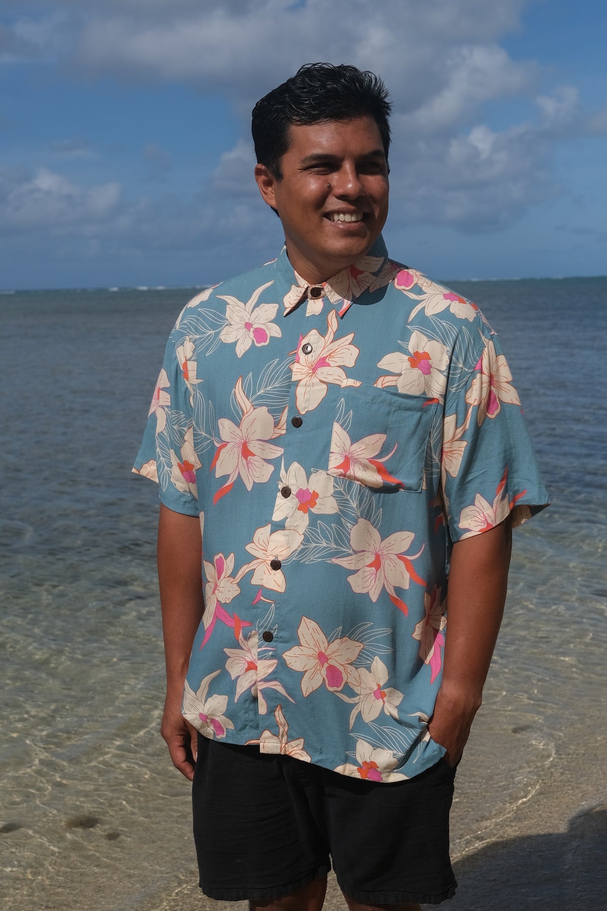man wearing a teal aloha button up shirt with cream colored orchid pattern