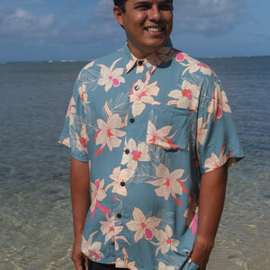 man wearing a teal aloha button up shirt with cream colored orchid pattern