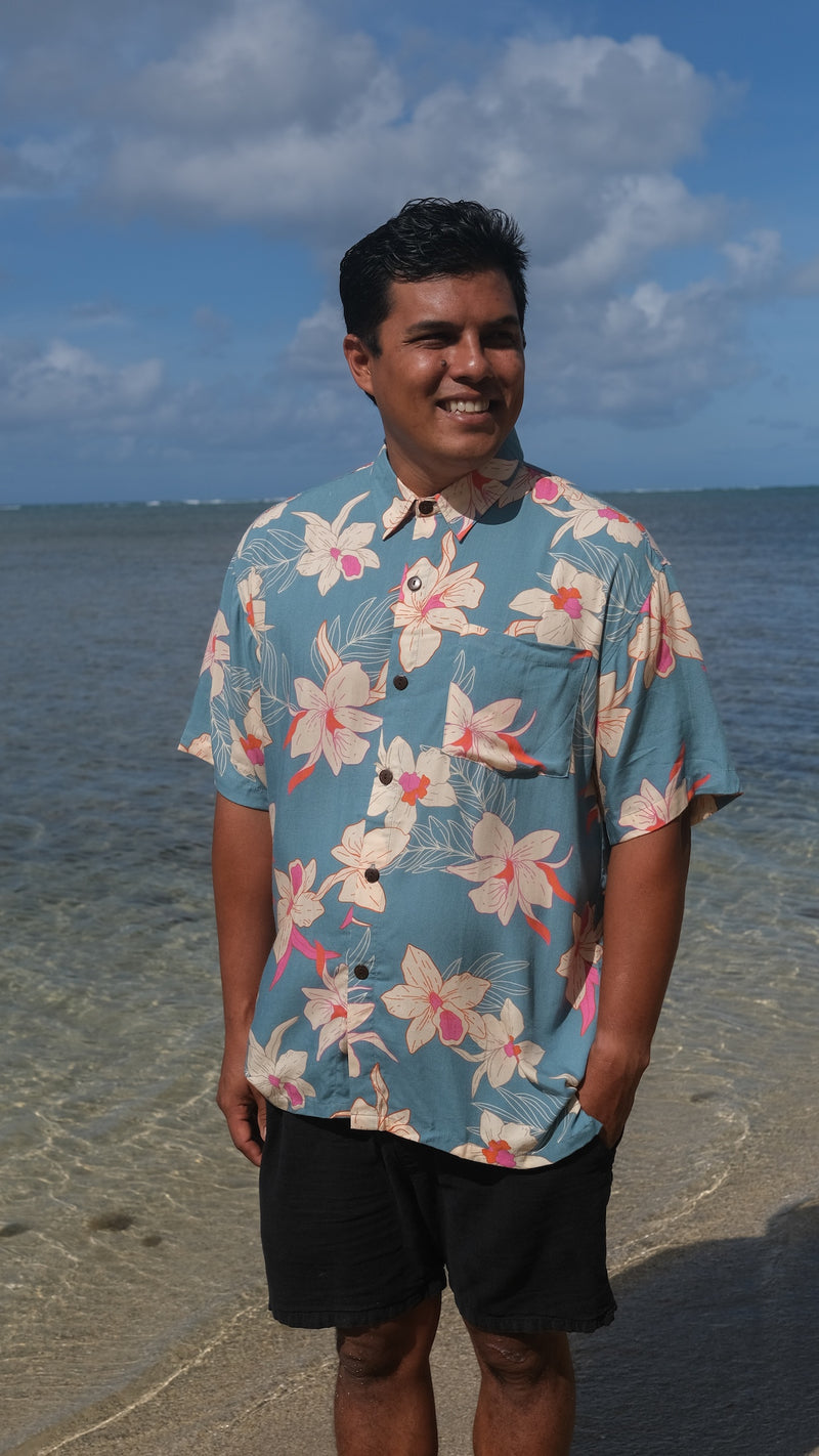 man wearing a teal aloha button up shirt with cream colored orchid pattern