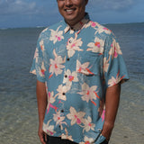 man wearing a teal aloha button up shirt with cream colored orchid pattern