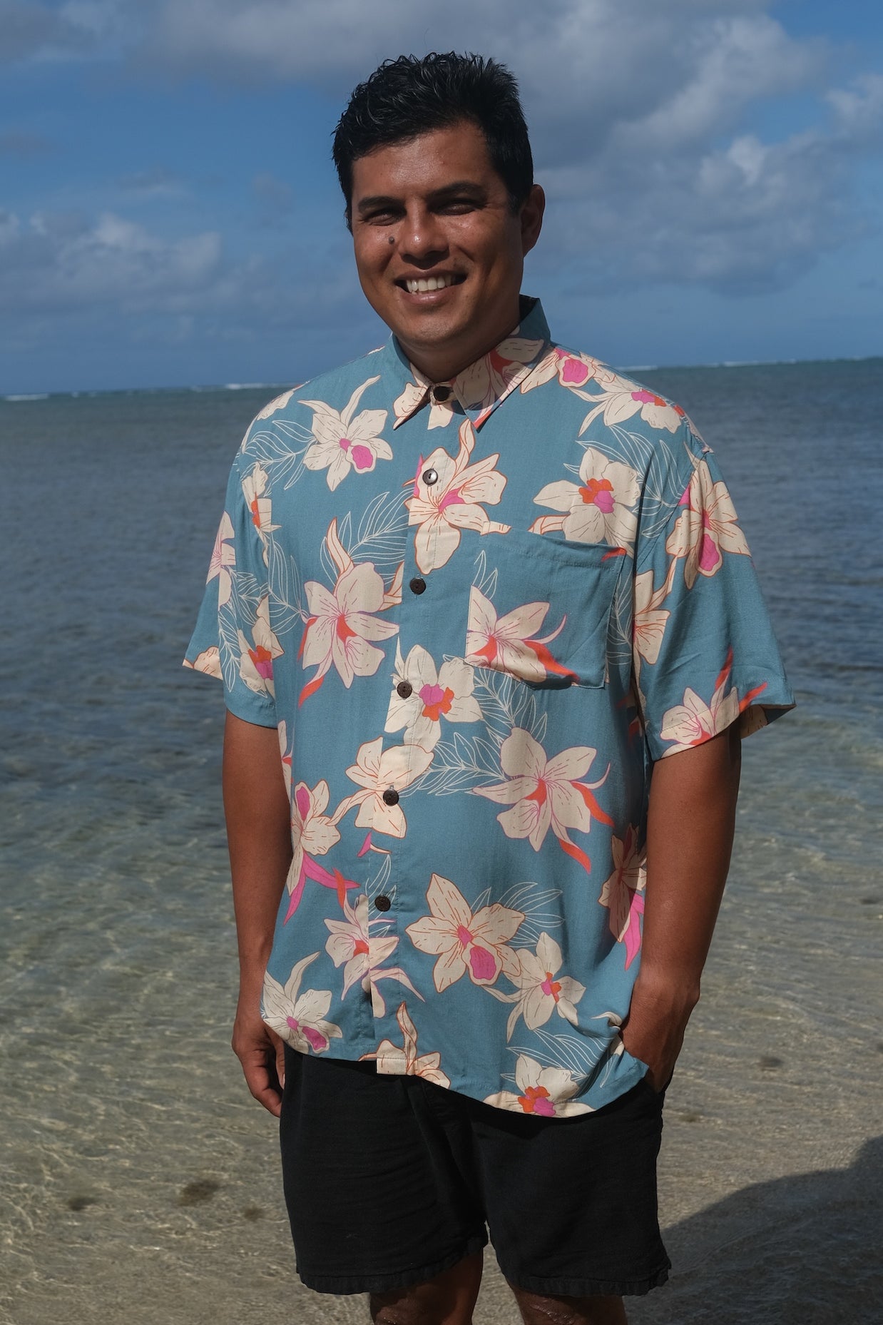 man wearing a teal aloha button up shirt with cream colored orchid pattern