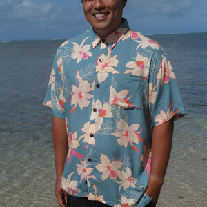 man wearing a teal aloha button up shirt with cream colored orchid pattern