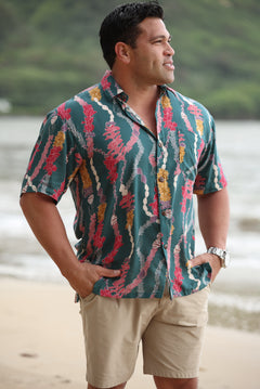 man with brown hair wearing dark teal aloha button up shirt with shell and lei print