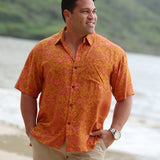 man with brown hair wearing an orange aloha button up shirt with puakenikeni print