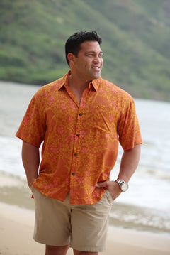 man with brown hair wearing an orange aloha button up shirt with puakenikeni print