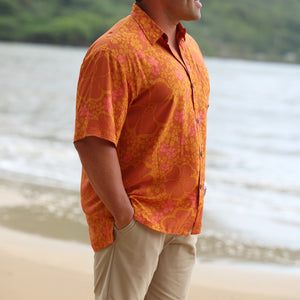 man with brown hair wearing an orange aloha button up shirt with puakenikeni print