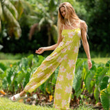 woman wearing a bright green tie back jumpsuit with orchid print