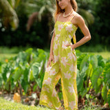 woman wearing a bright green tie back jumpsuit with orchid print