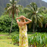 woman wearing a bright green tie back jumpsuit with orchid print