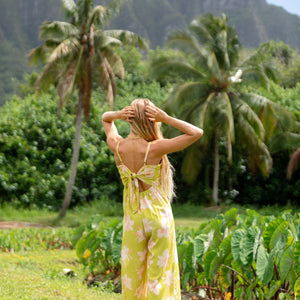 woman wearing a bright green tie back jumpsuit with orchid print