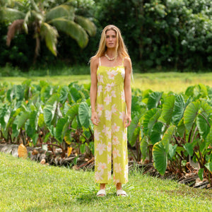 woman wearing a bright green tie back jumpsuit with orchid print
