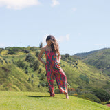 woman with brown hair wearing a colorful jumpsuit with tropical lei print