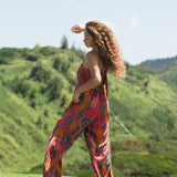 woman with brown hair wearing a colorful jumpsuit with tropical lei print