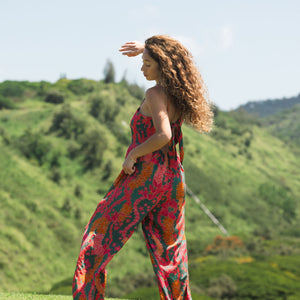 woman with brown hair wearing a colorful jumpsuit with tropical lei print