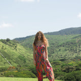 woman with brown hair wearing a colorful jumpsuit with tropical lei print