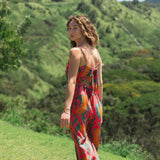 woman with brown hair wearing a colorful jumpsuit with tropical lei print