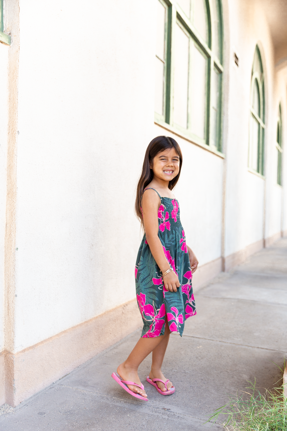 little girl with brown hair wearing a smocked spaghetti strap dress with fern and ginger print