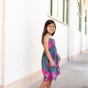 little girl with brown hair wearing a smocked spaghetti strap dress with fern and ginger print