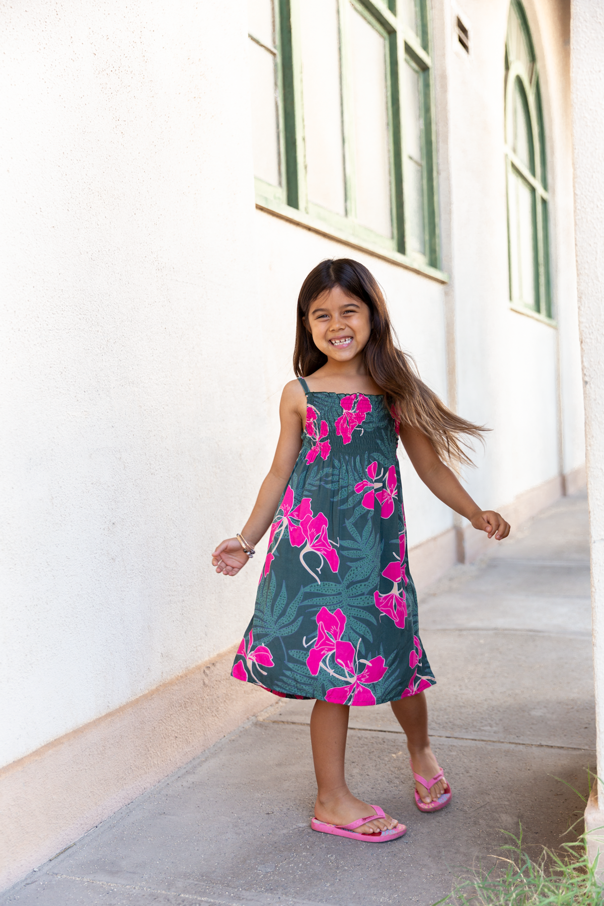 little girl with brown hair wearing a smocked spaghetti strap dress with fern and ginger print