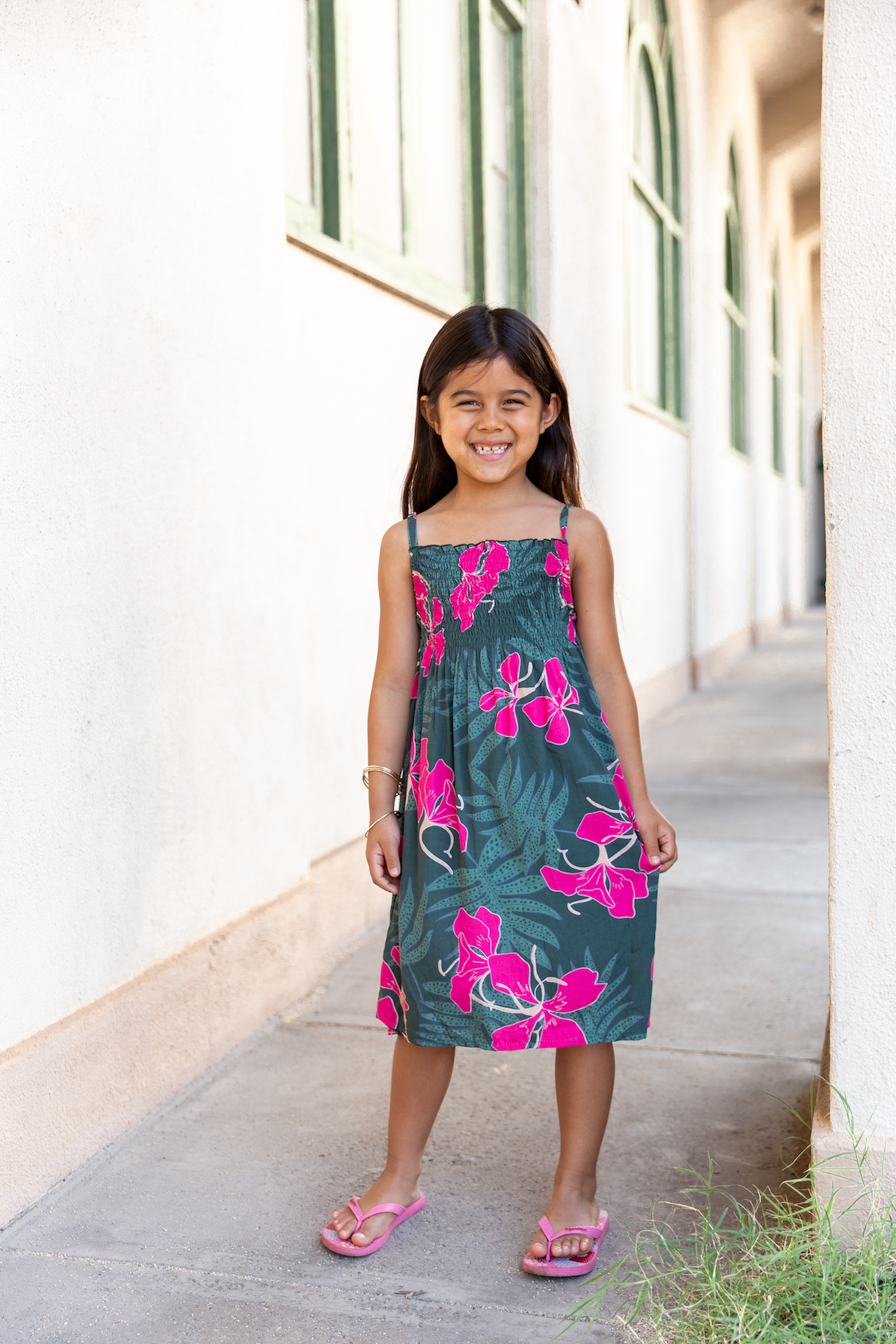little girl with brown hair wearing a smocked spaghetti strap dress with fern and ginger print