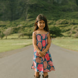 little girl wearing a navy spaghetti strap dress with bright pink hibiscus print