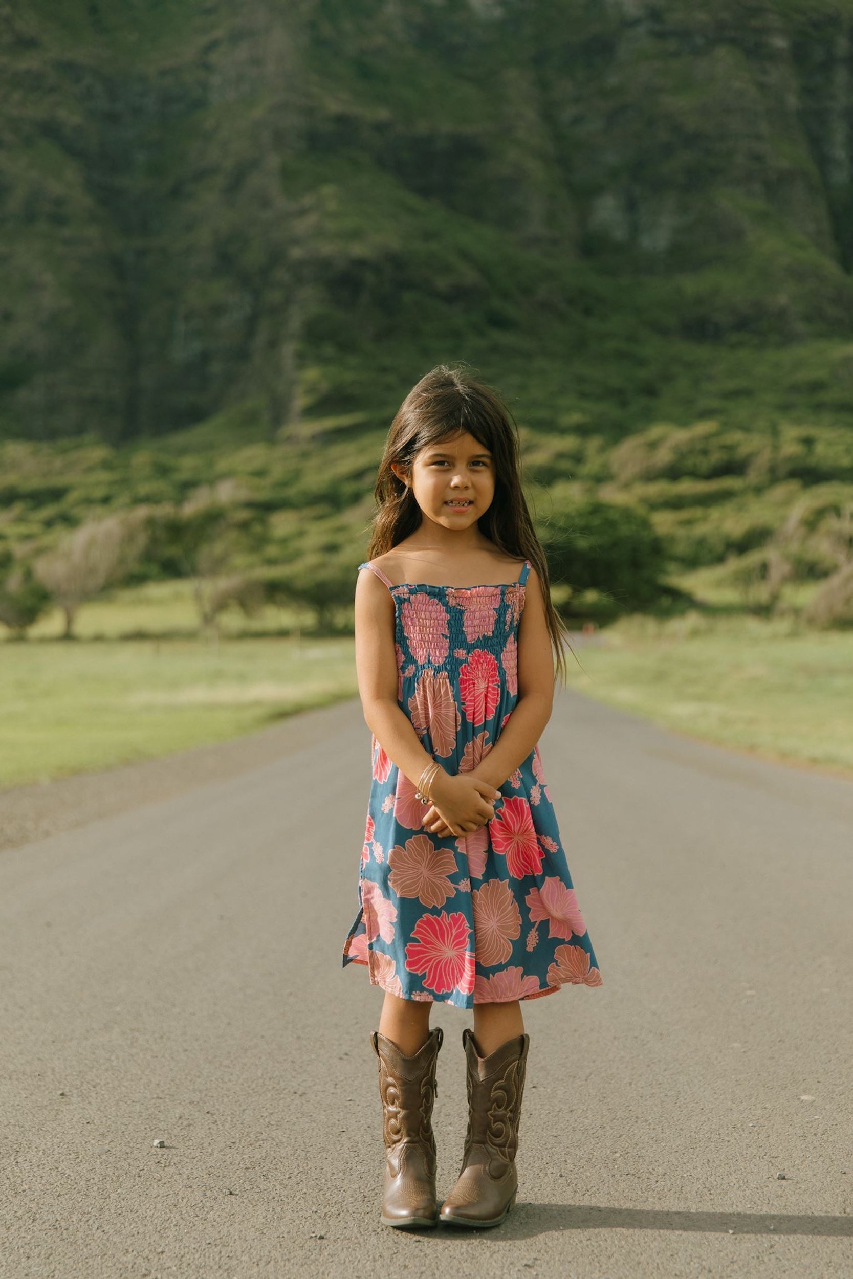 little girl wearing a navy spaghetti strap dress with bright pink hibiscus print