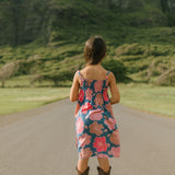 little girl wearing a navy spaghetti strap dress with bright pink hibiscus print