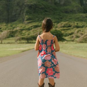 little girl wearing a navy spaghetti strap dress with bright pink hibiscus print