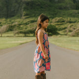 little girl wearing a navy spaghetti strap dress with bright pink hibiscus print