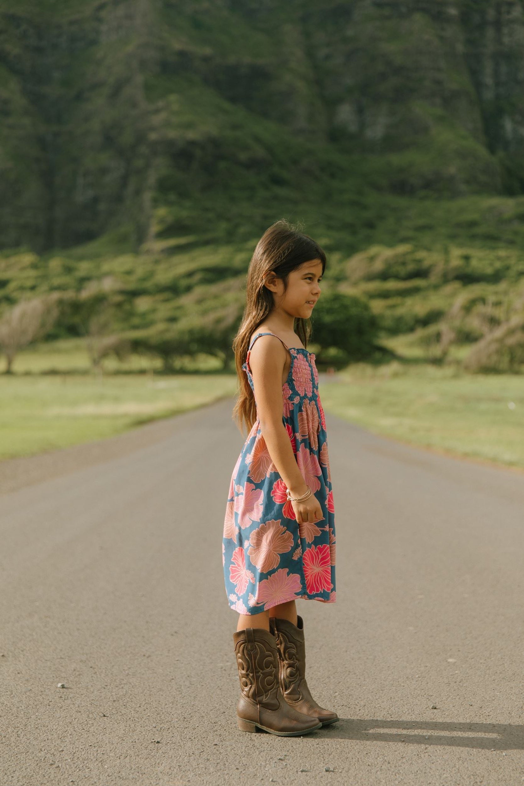 little girl wearing a navy spaghetti strap dress with bright pink hibiscus print