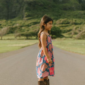 little girl wearing a navy spaghetti strap dress with bright pink hibiscus print