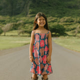 little girl wearing a navy spaghetti strap dress with bright pink hibiscus print