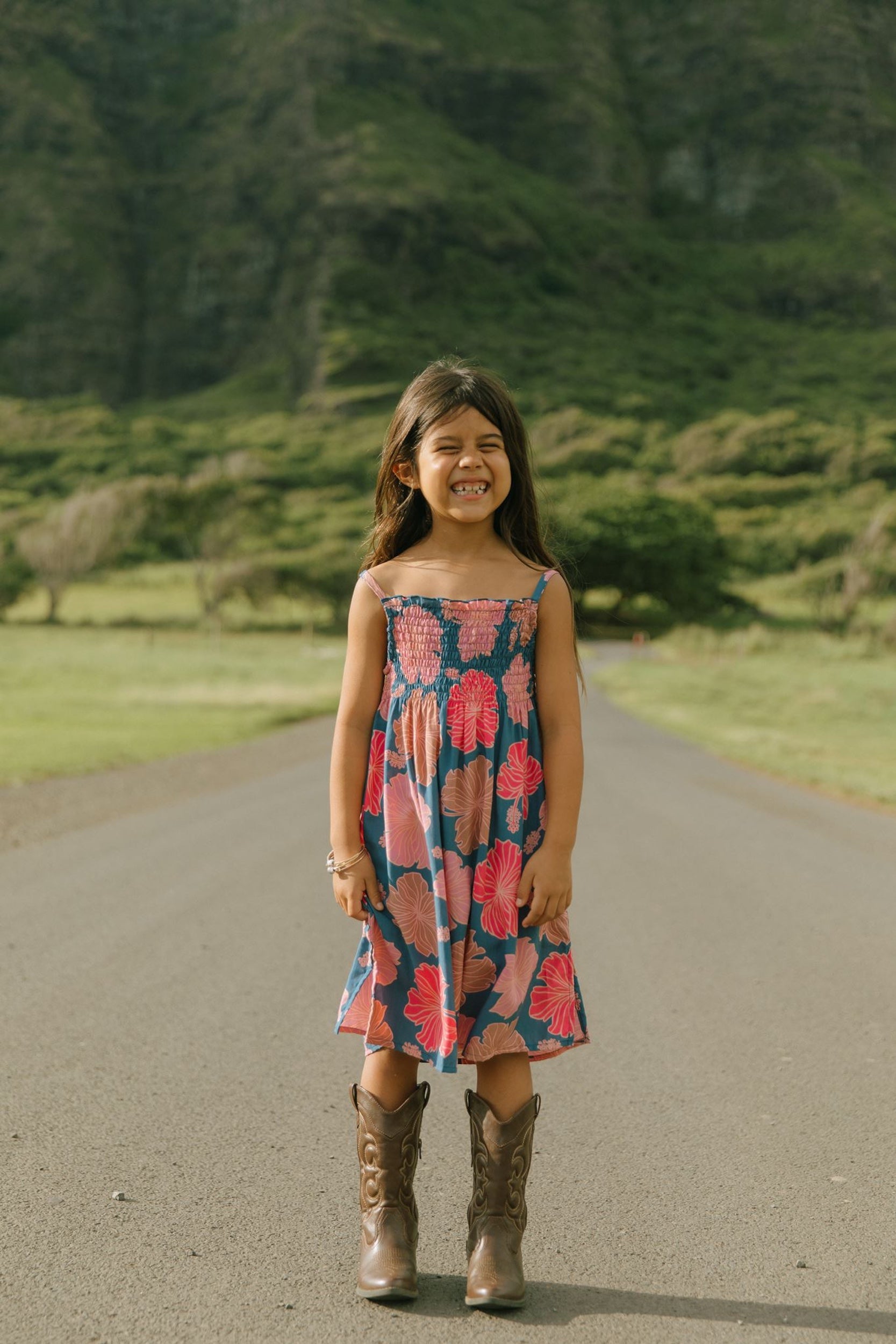 little girl wearing a navy spaghetti strap dress with bright pink hibiscus print