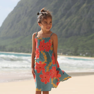little girl wearing a green knee length dress with orange and yellow lei pua print 