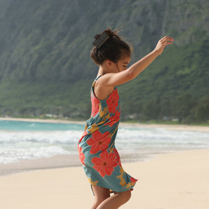 little girl wearing a green knee length dress with orange and yellow lei pua print 