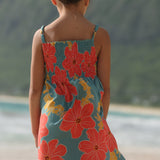 little girl wearing a green knee length dress with orange and yellow lei pua print 