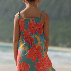 little girl wearing a green knee length dress with orange and yellow lei pua print 