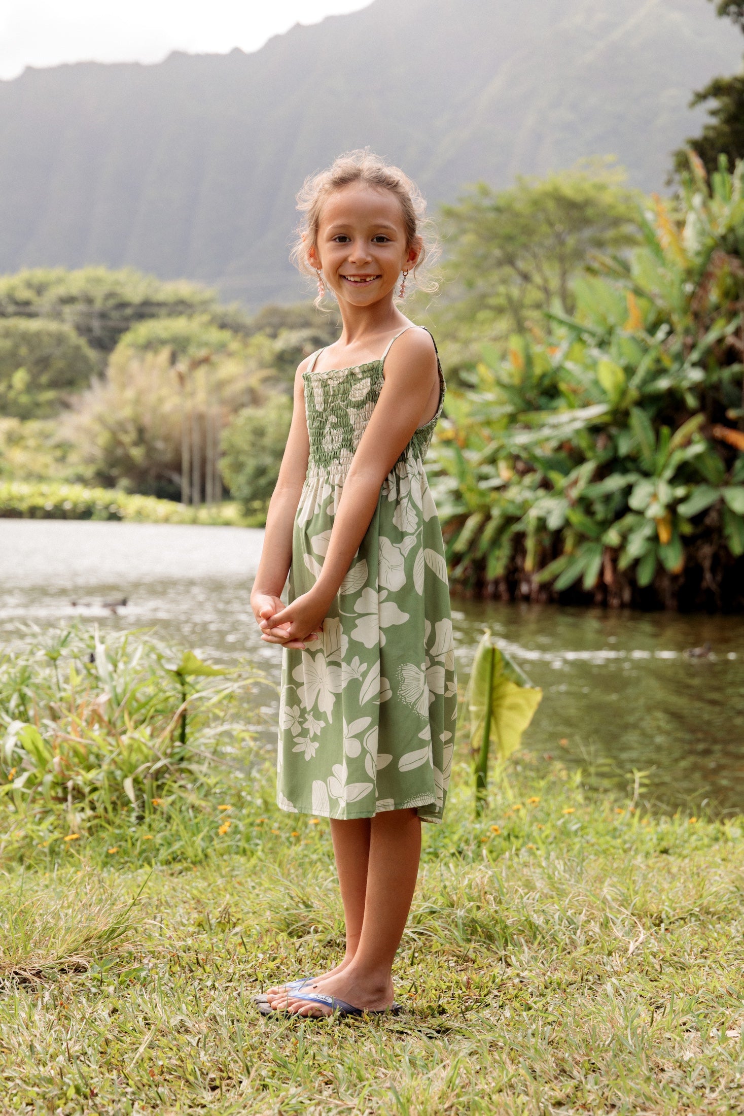little girl wearing green smocked dress with native Hawaiian plants