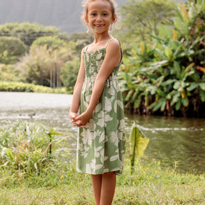 little girl wearing green smocked dress with native Hawaiian plants