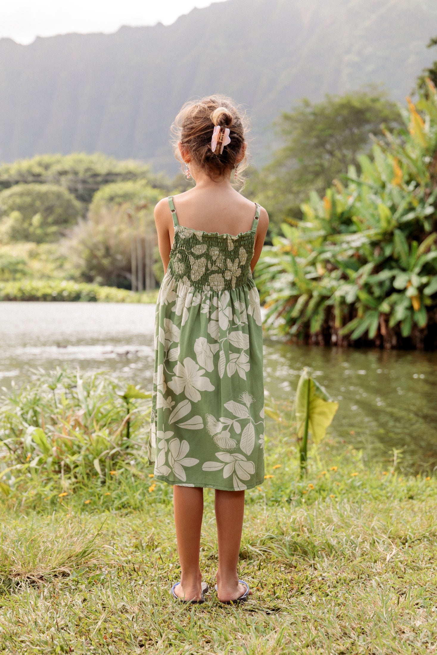 little girl wearing green smocked dress with native Hawaiian plants
