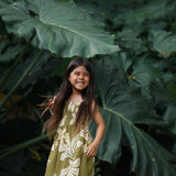 little girl wearing spaghetti strap dress in green print with naupaka pattern
