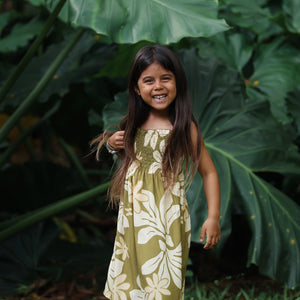 little girl wearing spaghetti strap dress in green print with naupaka pattern