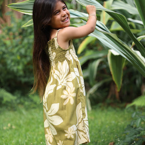 little girl wearing spaghetti strap dress in green print with naupaka pattern